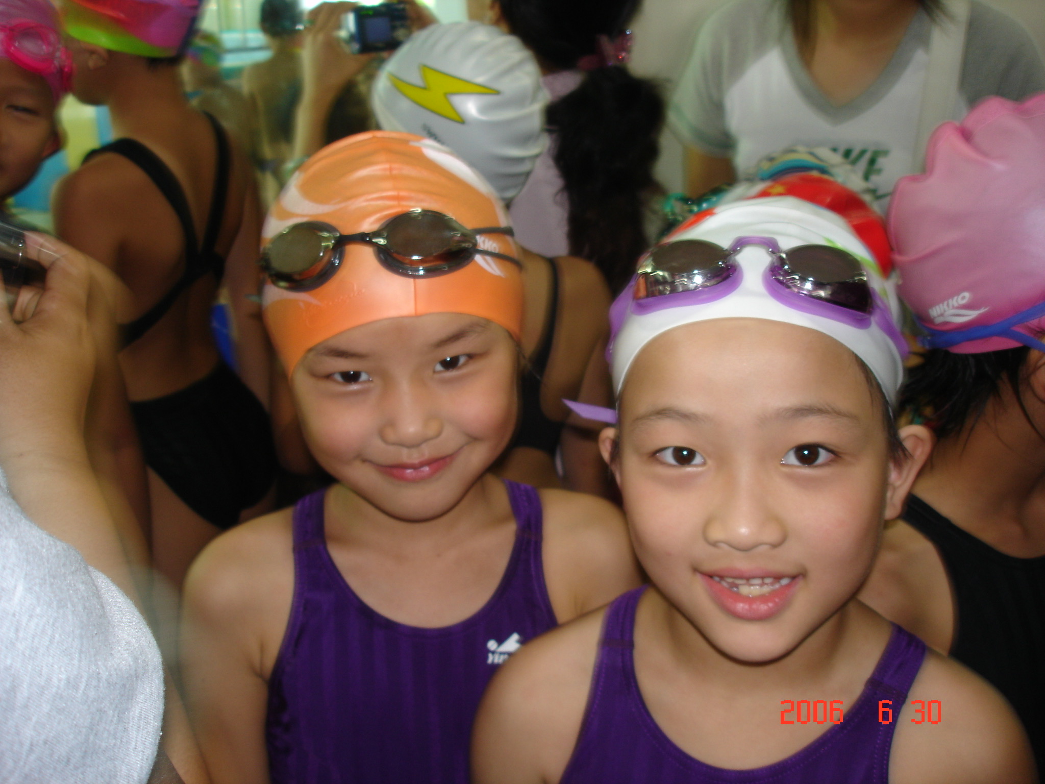 Two young swimmers wearing caps and goggles