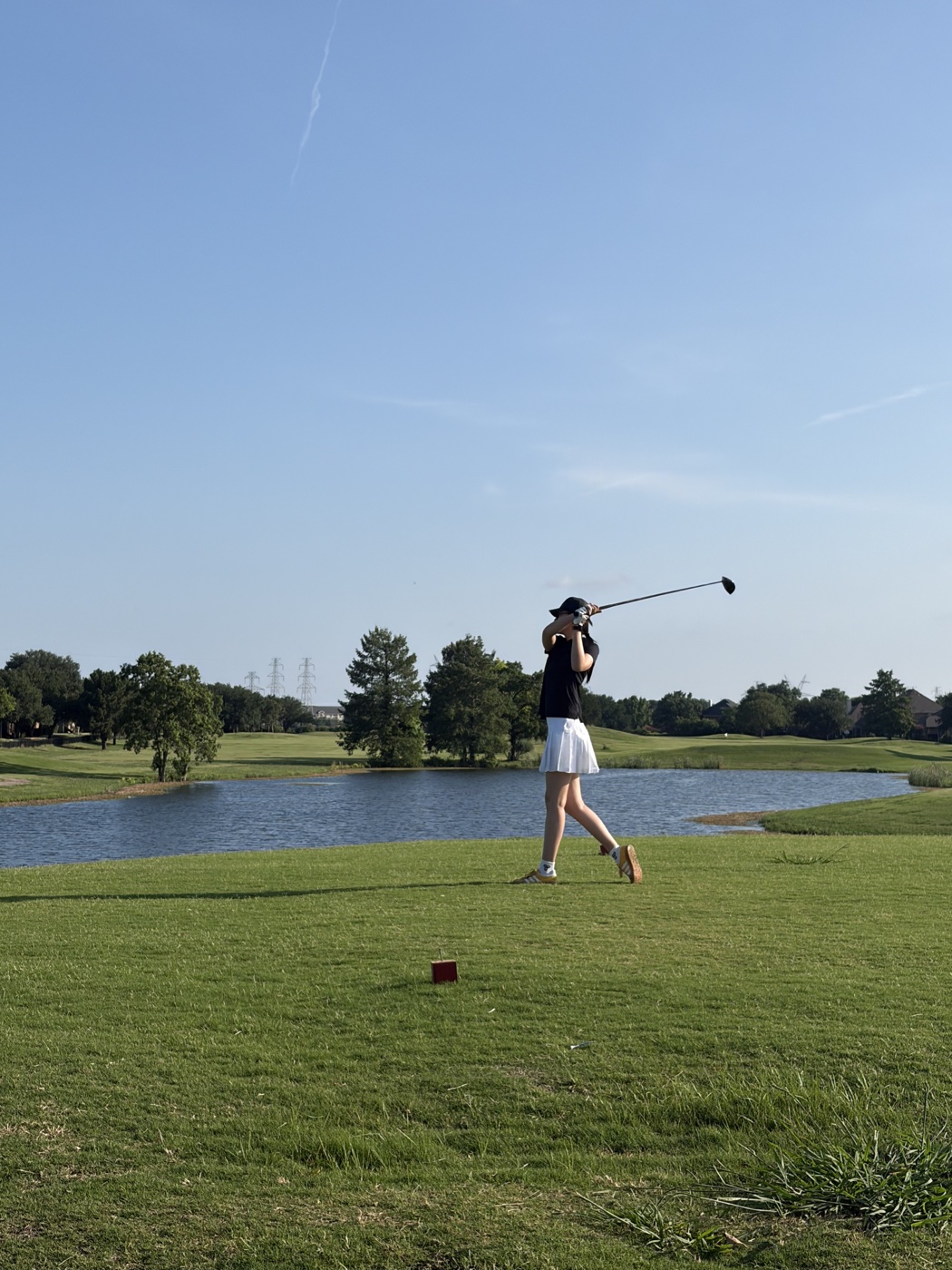 Yiwen finishing a golf swing beside the water